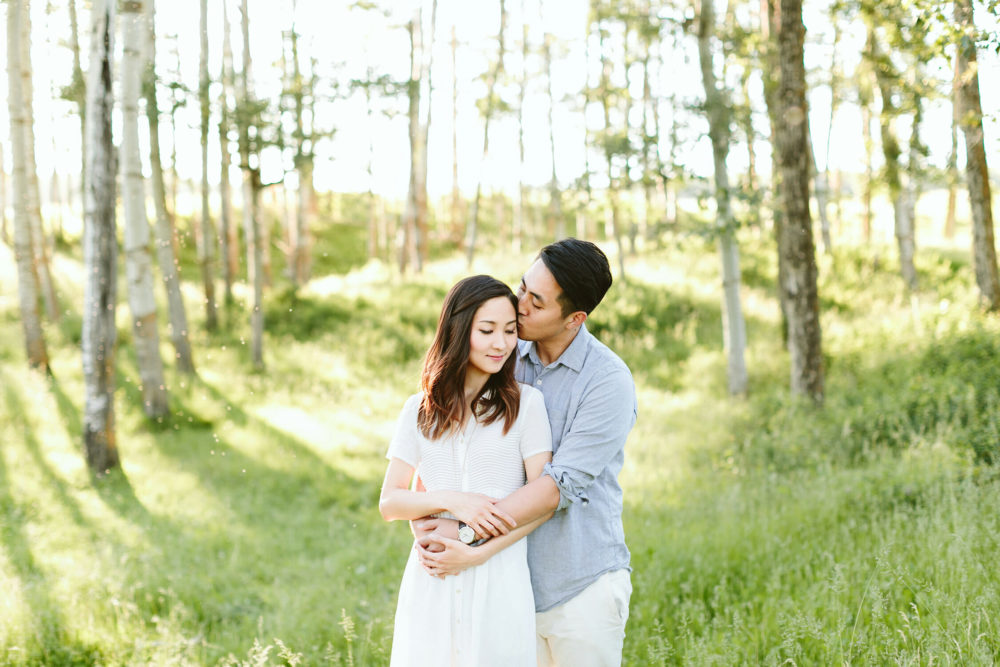 man kissing his fiancee in a meadow at their sylvan lake engagement session